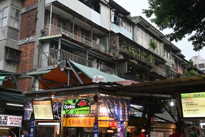 古い集合住宅の下に並ぶ南機場夜市の屋台。屋根の上に白い猫